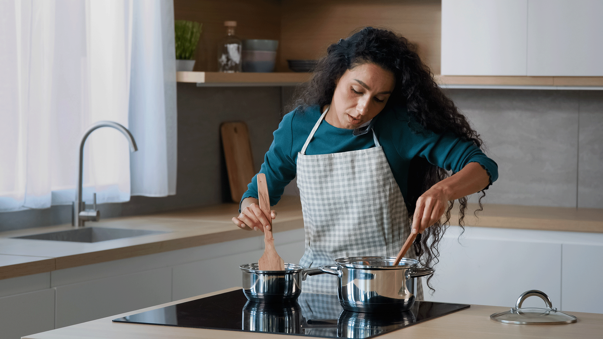Maya Thompson of Let's Make Cookies multitasking in her kitchen, stirring two pots on the stove while talking on the phone.