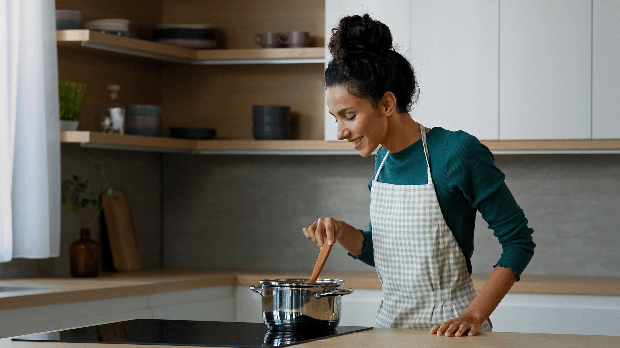 Maya Thompson smiling as she stirs a pot on her stove, enjoying the process of creating a new recipe for Let's Make Cookies.