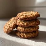 A stack of four soft banana oatmeal cookies with a slightly golden brown hue.