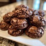 A pile of freshly baked brownie mix cookies with a fudgy texture and cracked tops.