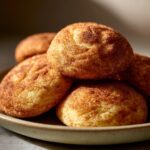 A close-up shot of a pile of freshly baked Christmas Snickerdoodles, coated in cinnamon sugar.