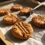 Close-up of freshly baked classic peanut butter cookies with fork marks on a baking sheet.