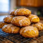 A stack of freshly baked maple pumpkin cookies with a light glaze on a cooling rack.